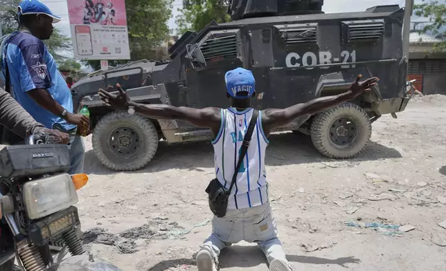 A resident of Cité Soleil kneels before a police armored vehicle and demands that the police go and fight the gangs that control their neighborhood, in Port-au-Prince, Haiti, Tuesday, May 12, 2026. (AP Photo/Odelyn Joseph)
