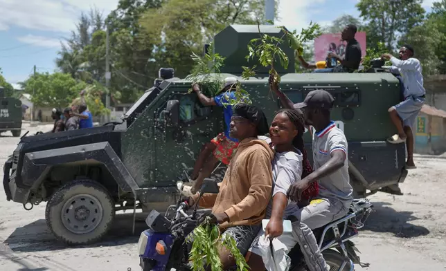 Residents of Cité Soleil celebrate the arrival of armored police vehicles during a protest to demand that police officers go and fight the gangs that control their neighborhood, in Port-au-Prince, Haiti, Tuesday, May 12, 2026. (AP Photo/Odelyn Joseph)
