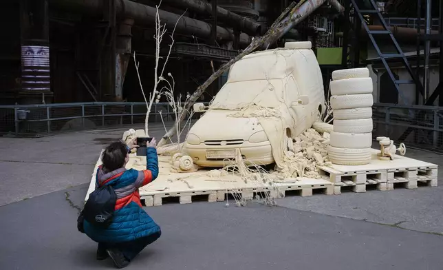 A woman takes a photo of the installation "Les Silence des Departs" by artist Tomas Lacque at the exhibition Urban Art Biennale 2026 at the former ironworks Voelklinger Huette, World Cultural Heritage Site, in Voelklingen, Germany, Wednesday, May 6, 2026. (Oliver Dietze/dpa via AP)