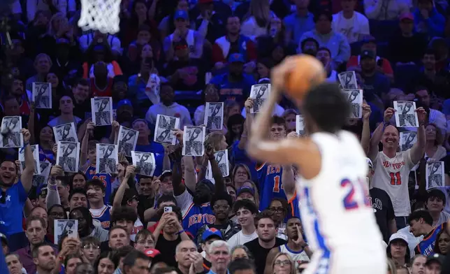 New York Knicks' fans hold up a photo as Philadelphia 76ers' Joel Embiid takes a free-throw shot during the first half of Game 4 against the New York Knicks in a second-round NBA basketball playoffs series Sunday, May 10, 2026, in Philadelphia. (AP Photo/Matt Slocum)