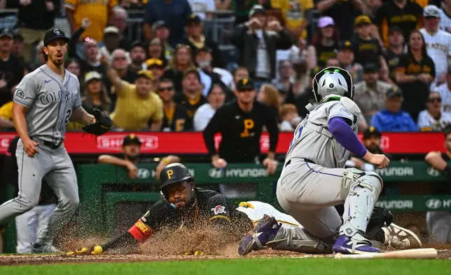 Pittsburgh Pirates' Oneil Cruz, left, slides safely under the tag by Colorado Rockies catcher Hunter Goodman to score on a single by Brandon Lowe during the fifth inning of a baseball game in Pittsburgh, Tuesday, May 12, 2026. (AP Photo/Justin Berl)