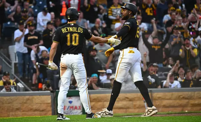 Pittsburgh Pirates' Oneil Cruz, left, celebrates with Bryan Reynolds after scoring on a single by Brandon Lowe during the fifth inning of a baseball game against the Colorado Rockies in Pittsburgh, Tuesday, May 12, 2026. (AP Photo/Justin Berl)