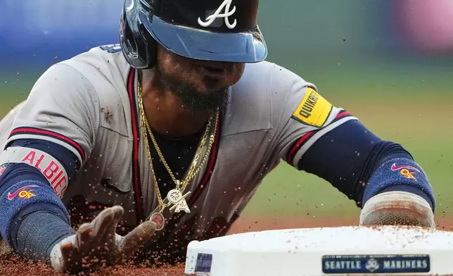 Atlanta Braves' Ozzie Albies slides into third base on a single from Matt Olson during the fourth inning of a baseball game against the Seattle Mariners, Tuesday, May 5, 2026, in Seattle. (AP Photo/Lindsey Wasson)