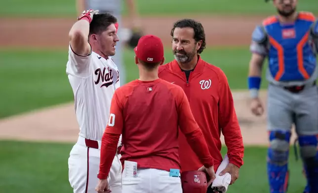 Washington Nationals' Jacob Young, left, is checked by manager Blake Butera, center, and head athletic trainer Dale Gilbert, third from left, after he was hit by a pitch during the second inning of a baseball game against the New York Mets, Monday, May 18, 2026, in Washington. (AP Photo/Jess Rapfogel)