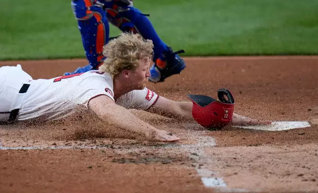 Washington Nationals' Joey Wiemer slides into home plate as he scores against the New York Mets on a double hit by José Tena during the second inning of a baseball game, Monday, May 18, 2026, in Washington. (AP Photo/Jess Rapfogel)