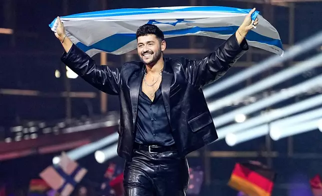 Noam Bettan from Israel walks onto the stage carrying his countries flag ahead of the Grand Final of the 70th Eurovision Song Contest in Vienna, Austria, Saturday, May 16, 2026. (AP Photo/Martin Meissner)