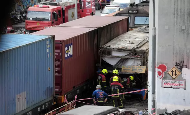 First responders work at a train crash site near an airport rail link station in Bangkok, Thailand, Saturday, May 16, 2026. (AP Photo/Sakchai Lalit)