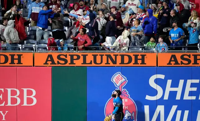 Philadelphia Phillies' Brandon Marsh watches as fans reach for a home run by Cleveland Guardians' Kyle Manzardo during the ninth inning of a baseball game Friday, May 22, 2026, in Philadelphia. (AP Photo/Matt Slocum)
