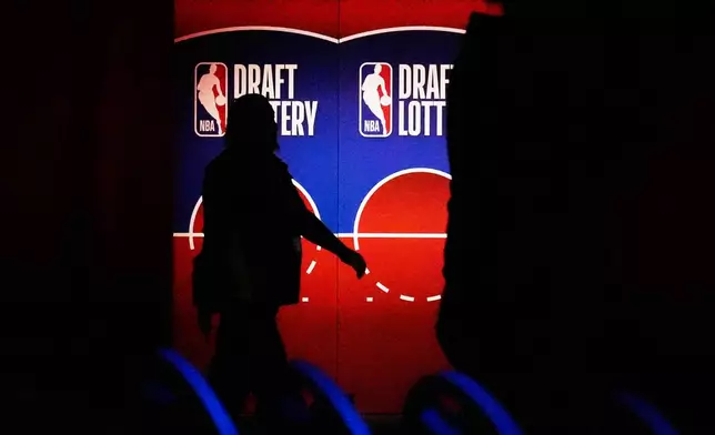 A person walks by a sign in the NBA basketball draft lottery in Chicago, Sunday, May 10, 2026. (AP Photo/Nam Y. Huh)