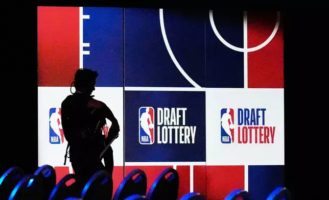 A person walks by a sign in the NBA basketball draft lottery in Chicago, Sunday, May 10, 2026. (AP Photo/Nam Y. Huh)