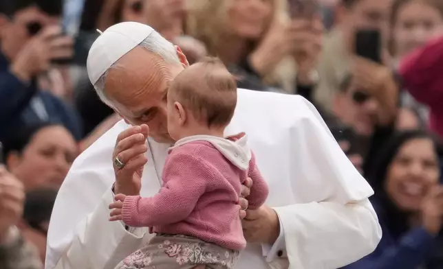 Pope Leo XIV blesses a child as he arrives for his weekly general audience in St. Peter's Square, at the Vatican, Wednesday, May 6, 2026. (AP Photo/Gregorio Borgia)