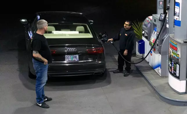 An attendant talks with a customer while fueling their tank at a gas station on Wednesday, May 6, 2026, in Portland, Ore. (AP Photo/Jenny Kane)