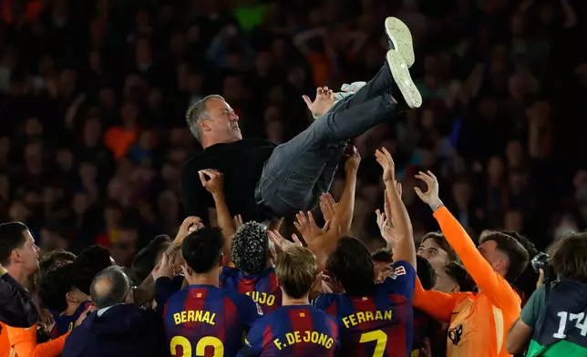 Barcelona head coach Hansi Flick is lifted by his players after winning the Spanish La Liga soccer match against Real Madrid to clinch the Spanish league title in Barcelona, Spain, Sunday, May 10, 2026. (AP Photo/Joan Monfort)
