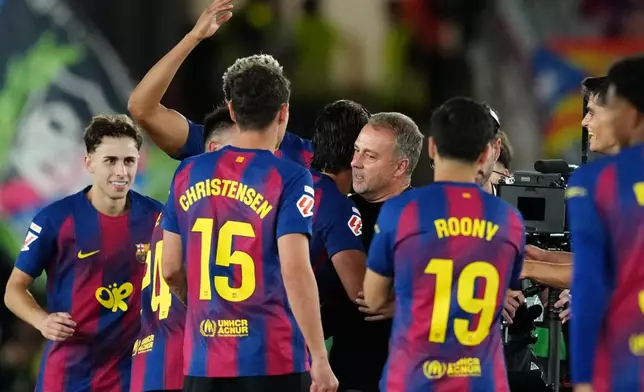 Barcelona players embrace Barcelona head coach Hansi Flick, center, celebrating after defeating Real Madrid 2-0 to win the Spanish La Liga soccer championship with three rounds to spare, in Barcelona, Spain, Sunday, May 10, 2026. (AP Photo/Joan Mateu Parra)