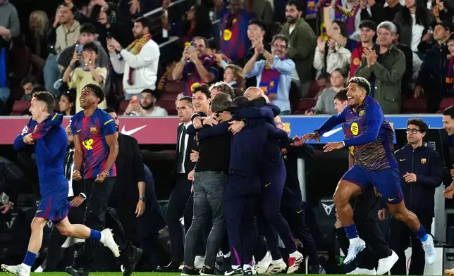 Barcelona head coach Hansi Flick, center, is embraced by his staff celebrating after defeating Real Madrid 2-0 to win the Spanish La Liga soccer championship with three rounds to spare, in Barcelona, Spain, Sunday, May 10, 2026. (AP Photo/Joan Mateu Parra)