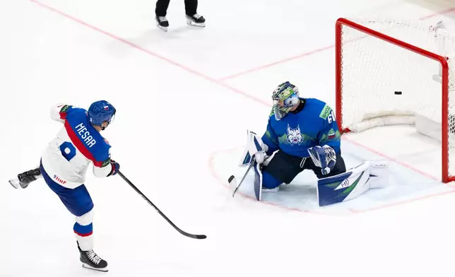Slovakia's Filip Mesar, left, scores the winning goal past Slovenia's goaltender Lukas Horak during a shootout during the Group B preliminary round game between Italy and Norway at the men's ice hockey world Championship in Fribourg, Switzerland, Tuesday, May 19, 2026. (Anthony Anex/Keystone via AP)
