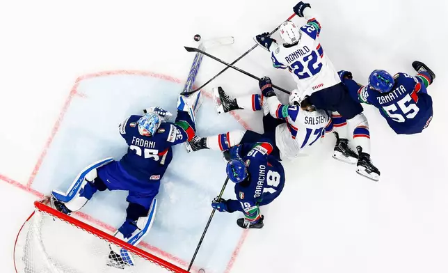 Italy's goaltender Davide Fadani, left, Nicholas Saracino, second left, and Luca Zanatta, right, challenge Norway's Eirik Salsten, center, and Martin Ronnild during the Men's Ice Hockey World Championship preliminary round match between Italy and Norway in Fribourg, Switzerland, Tuesday, May 19, 2026. (Anthony Anex/Keystone via AP)