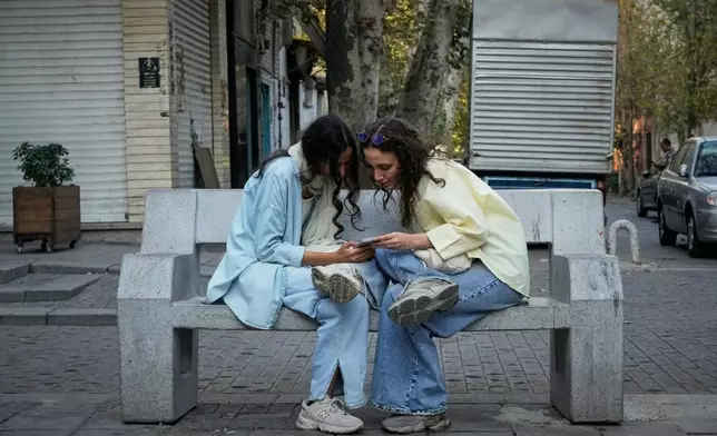 FILE - Two women use a smartphone in northern Tehran, Iran, Sept. 28, 2025. (AP Photo/Vahid Salemi, File)