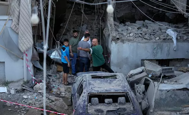 People gather outside a destroyed apartment that was hit in an Israeli airstrike in the southern port city of Sidon, Lebanon, Thursday, May 28, 2026. (AP Photo/Mohammed Zaatari)