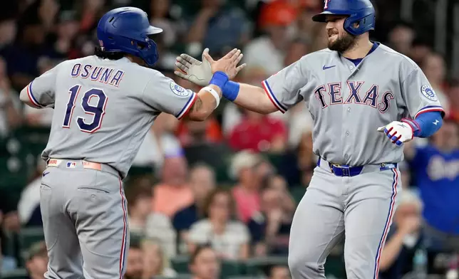 Texas Rangers' Jake Burger, right, celebrates with Alejandro Osuna (19) after hitting a two-run home run against the Houston Astros during the fifth inning of a baseball game, Sunday, May 17, 2026, in Houston. (AP Photo/Eric Christian Smith)