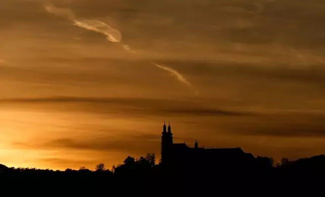 The suns sets behind the catholic monastery church of Banz in Bad Staffelstein, Germany, Saturday, May 2, 2026. (AP Photo/Matthias Schrader)