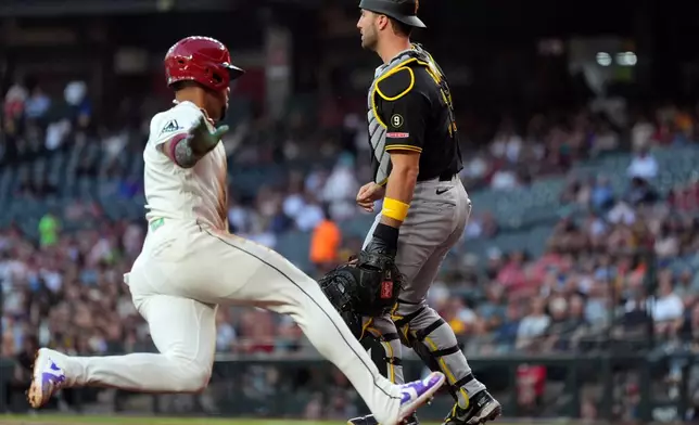 Arizona Diamondbacks' Ketel Marte, left, scores a run as Pittsburgh Pirates catcher Joey Bart waits for a late throw during the first inning of a baseball game, Tuesday, May 5, 2026, in Phoenix. (AP Photo/Ross D. Franklin)