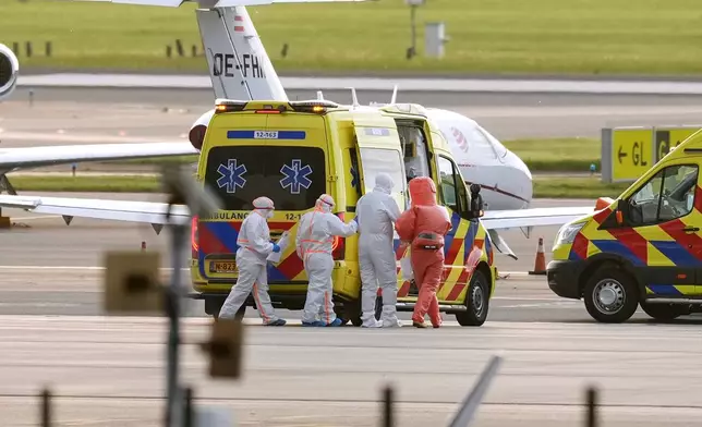 Medics escort a patients, evacuated from the MV Hondius cruise ship with suspected hantavirus infection, to an ambulance after being flown to Schiphol airport, Amsterdam, Netherlands, Wednesday, May 6, 2026. (AP Photo/Peter Dejong)