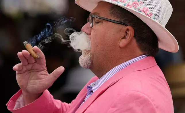 Paul Anderson smokes a cigar before the 152nd running of the Kentucky Derby horse race at Churchill Downs, Saturday, May 2, 2026, in Louisville, Ky. (AP Photo/Charlie Riedel)