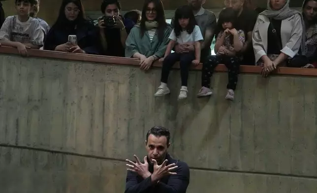 Ali Barati dances during a music performance dubbed "Sounds of the South," featuring music from southern Iran, as people watch at the Tehran Museum of Contemporary Art in Tehran, Iran, Thursday, May 21, 2026. (AP Photo/Vahid Salemi)