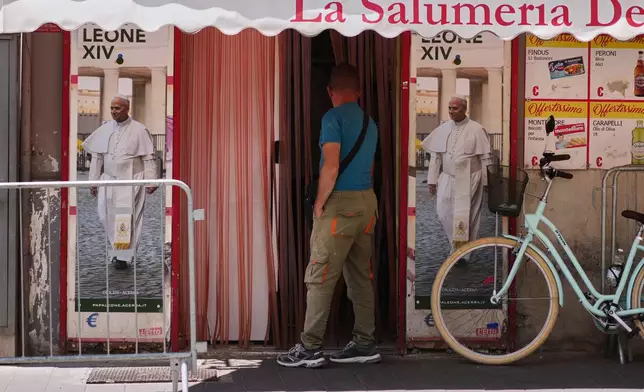 A man enters a grocery store with posters of Pope Leo XIV ahead of his visit to the southern Italian town of Acerra in the Terra dei Fuochi, or Land of Fires, Friday, May 22, 2026. (AP Photo/Andrew Medichini)