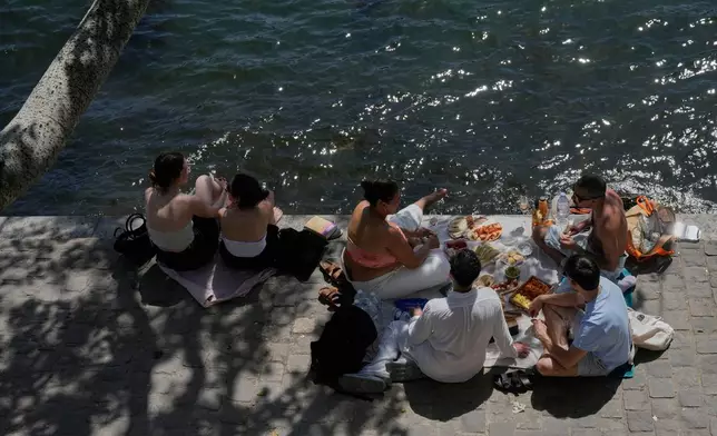 People picnics in along the Seine River during sunny day in Paris, Monday, May 25, 2026. (AP Photo/Michel Euler)