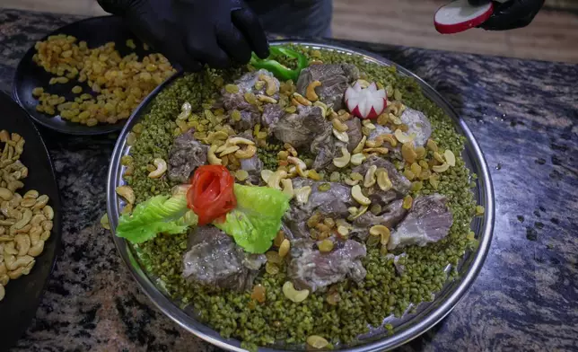 A cook prepares a dish made with freekeh, a roasted green wheat grain widely used in Levantine cuisine and made by harvesting immature wheat and roasting it over open flames to separate and preserve the grains, at a restaurant in Idlib, Syria, Sunday, May 24, 2026. (AP Photo/Ghaith Alsayed)