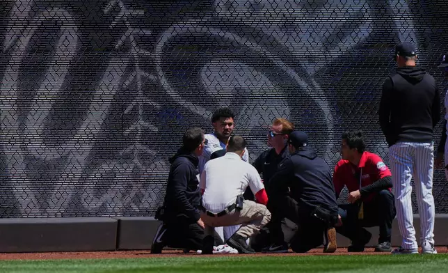 New York Yankees manager Aaron Boone, right, watches as trainers and paramedics check on left fielder Jasson Domínguez after he was injured during the first inning of a baseball game against the Texas Rangers Thursday, May 7, 2026, in New York. (AP Photo/Frank Franklin II)