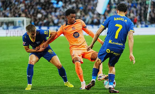 Barcelona's Alejandro Balde, center, fights for the ball with Alaves' Angel Perez, right, and Antonio Blanco during the Spanish La Liga soccer match between Alaves and Barcelona in Vitoria-Gasteiz, Spain, Wednesday, May 13, 2026. (AP Photo/Miguel Oses)