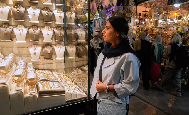 A woman looks at jewelry in the window of a gold shop at Tehran's historic Grand Bazaar, Iran, Sunday, May 3, 2026. (AP Photo/Vahid Salemi)