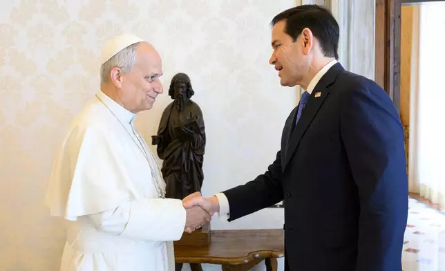 In this handout photo provided by Vatican Media Pope Leo XIV greets U.S. Secretary of State Marco Rubio, right, upon his arrival for talks in the pope's private library at the Vatican, Thursday, May 7, 2026. (Vatican Media via AP)