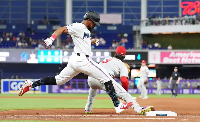 Miami Marlins' Otto Lopez, left, makes it safely to first past Philadelphia Phillies first baseman Bryce Harper during the fourth inning of a baseball game, Monday, May 4, 2026, in Miami. (AP Photo/Rebecca Blackwell)