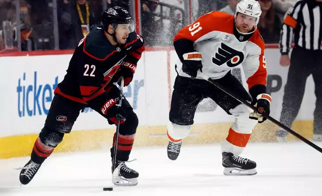 Carolina Hurricanes' Logan Stankoven (22) moves the puck near Philadelphia Flyers' Carl Grundstrom (91) during the third period of Game 2 of an NHL hockey Stanley Cup second-round playoff series in Raleigh, N.C., Monday, May 4, 2026. (AP Photo/Karl DeBlaker)