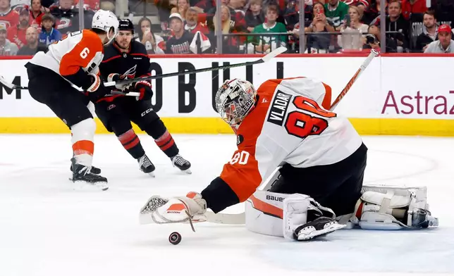Philadelphia Flyers goaltender Dan Vladar (80) freezes the puck in front of teammate Travis Sanheim (6) and Carolina Hurricanes' Logan Stankoven, back right, during the second period of Game 2 of an NHL hockey Stanley Cup second-round playoff series in Raleigh, N.C., Monday, May 4, 2026. (AP Photo/Karl DeBlaker)