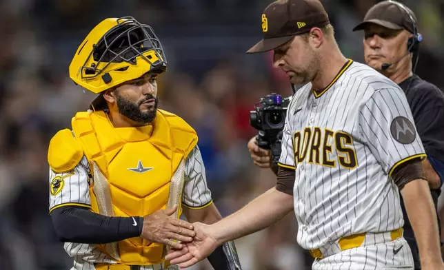 San Diego Padres catcher Rodolfo Durán, left, gives a hand to starting pitcher Michael King, front right, after the in the sixth inning of a baseball game against the Los Angeles Dodgers, Monday, May 18, 2026, in San Diego. (AP Photo/Tony Ding)
