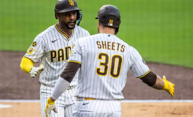 San Diego Padres' Miguel Andujar, left, celebrates his home run hit in the first inning with Gavin Sheets (30) in a baseball game against the Los Angeles Dodgers, Monday, May 18, 2026, in San Diego. (AP Photo/Tony Ding)