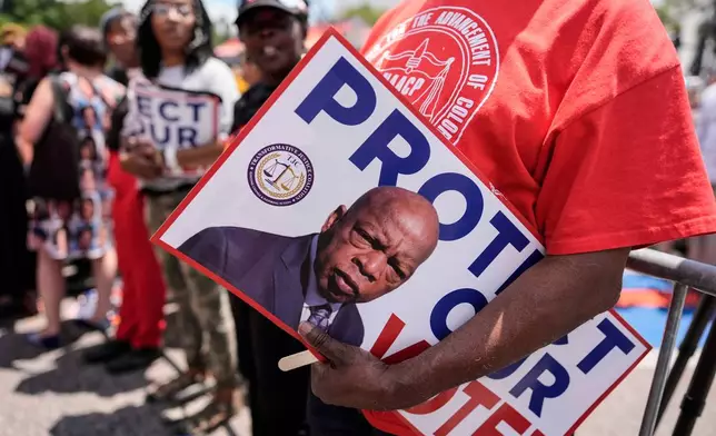 A protestor holds a sign of the late Georgia Congressman John Lewis during a voting rally, Saturday, May 16, 2026, in Montgomery, Ala. (AP Photo/Mike Stewart)
