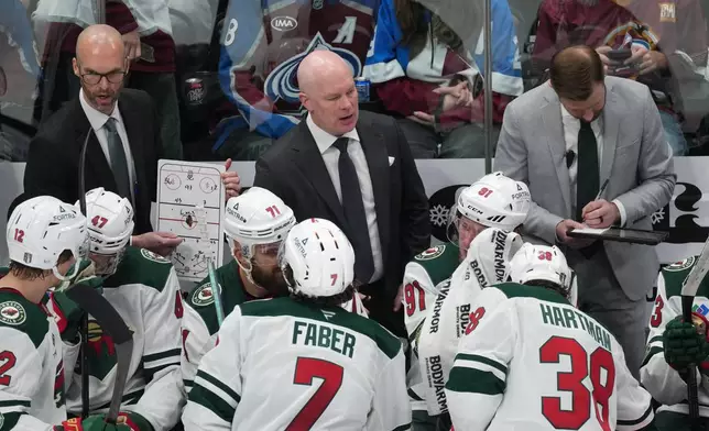 Minnesota Wild head coach John Hynes, back center, confers with players during a time out as assistant coaches Jason King, back left, and Patrick Dwyer join in in the third period of Game 1 of an NHL hockey Stanley Cup second-round playoff series against the Colorado Avalanche Sunday, May 3, 2026, in Denver. (AP Photo/David Zalubowski)