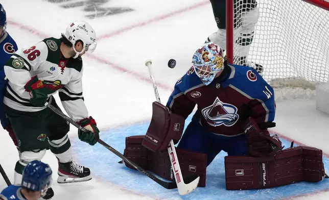 Minnesota Wild right wing Mats Zuccarello, left, redirects the puck at Colorado Avalanche goaltender Scott Wedgewood in the third period of Game 1 of an NHL hockey Stanley Cup second-round playoff series Sunday, May 3, 2026, in Denver. (AP Photo/David Zalubowski)