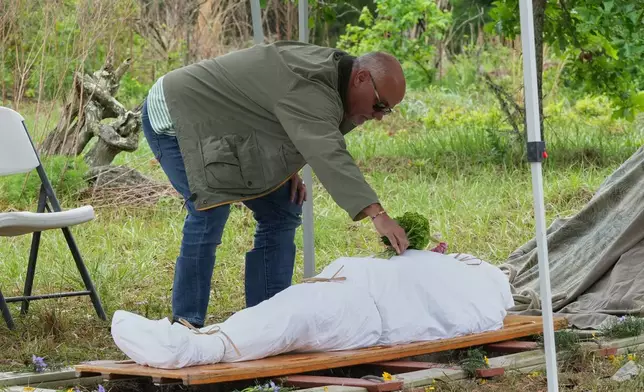 Scott King places a bouquet of flowers on the body of his brother Kenneth King at the Prairie Creek Conservation Cemetery, Tuesday, April 7, 2026, in Gainesville, Fla. (AP Photo/Marta Lavandier)