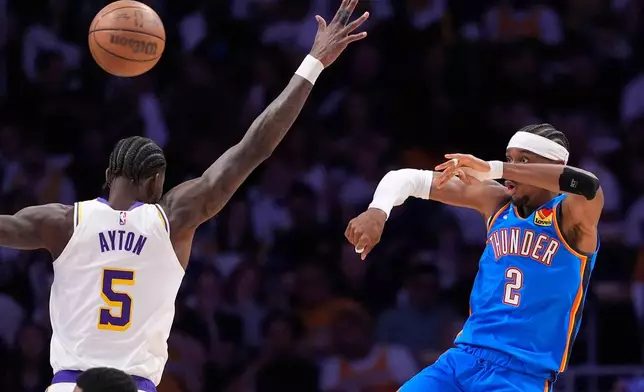 Oklahoma City Thunder guard Shai Gilgeous-Alexander, right, passes the ball as Los Angeles Lakers center Deandre Ayton defends during the first half of Game 3 in a second-round NBA basketball playoffs series Saturday, May 9, 2026, in Los Angeles. (AP Photo/Mark J. Terrill)