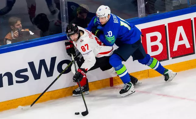 Canada's Sidney Crosby, left, vies for the puck against Slovenia's Miha Bericic, right, during a preliminary round game between Canada and Slovenia at the men's ice hockey world championship in Fribourg, Switzerland, Friday May 22, 2026. (Salvatore Di Nolfi/Keystone via AP)