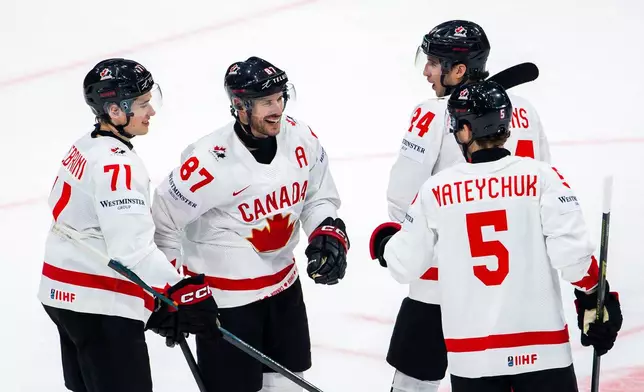 Canada's Dylan Cozens, second right, celebrates his goal with his teammates Canada's Canada's Macklin Celebrini, left, Sidney Crosby, left, and Canada's Denton Mateychuk, right, centre, after scoring during a preliminary round game between Canada and Slovenia at the men's ice hockey world championship in Fribourg, Switzerland, Friday May 22, 2026. (Salvatore Di Nolfi/Keystone via AP)