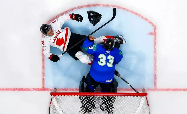 Canada's Emmitt Finnie, left, clashes against Slovenia's goaltender Zan Us, right, during a preliminary round game between Canada and Slovenia at the men's ice hockey world championship in Fribourg, Switzerland, Friday May 22, 2026. (Salvatore Di Nolfi/Keystone via AP)