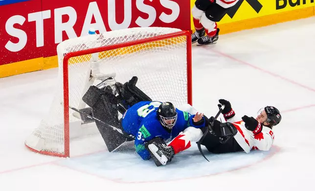 Canada's Emmitt Finnie, right, clashes against Slovenia's goaltender Zan Us during a preliminary round game between Canada and Slovenia at the men's ice hockey world championship in Fribourg, Switzerland, Friday May 22, 2026. (Salvatore Di Nolfi/Keystone via AP)